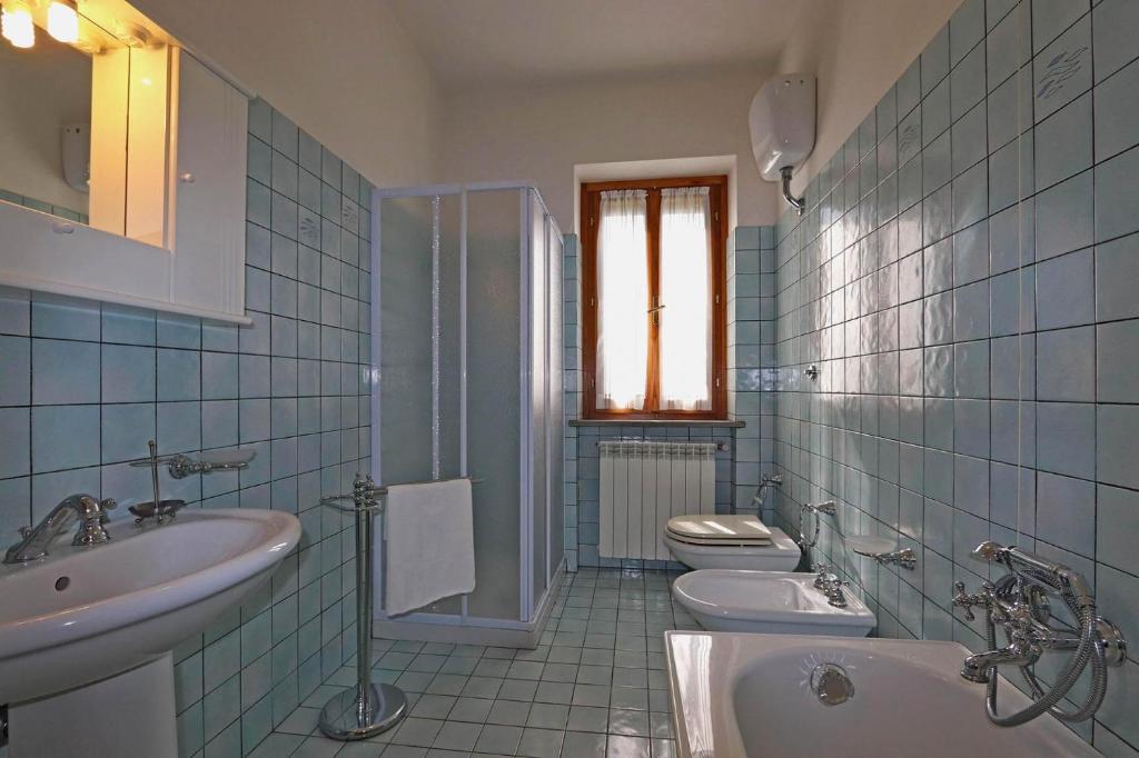 - une salle de bains carrelée de bleu avec 2 toilettes et un lavabo dans l'établissement Casale Lucy, à Pergola