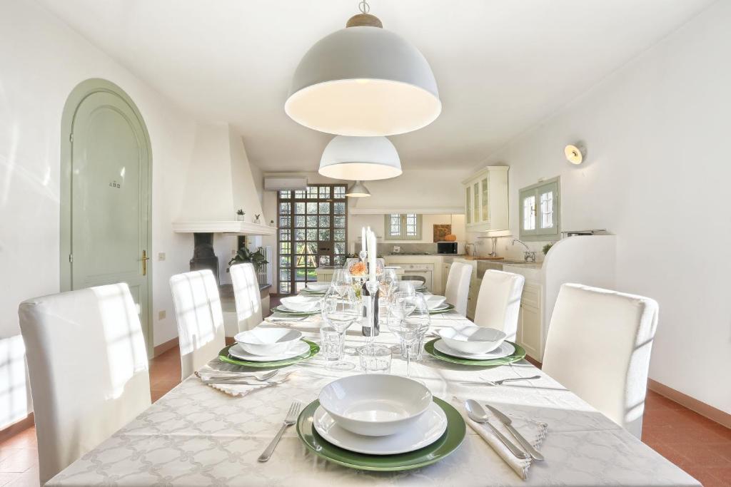 une salle à manger avec une table et des chaises blanches dans l'établissement Villa Maona - con piscina tra Firenze e Pisa, à Montecatini Terme