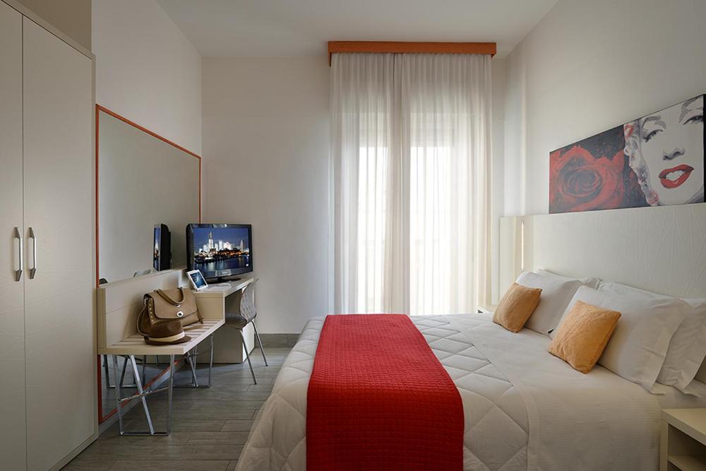 une chambre avec un lit, un bureau et une télévision dans l'établissement Hotel Tiberius, à Rimini