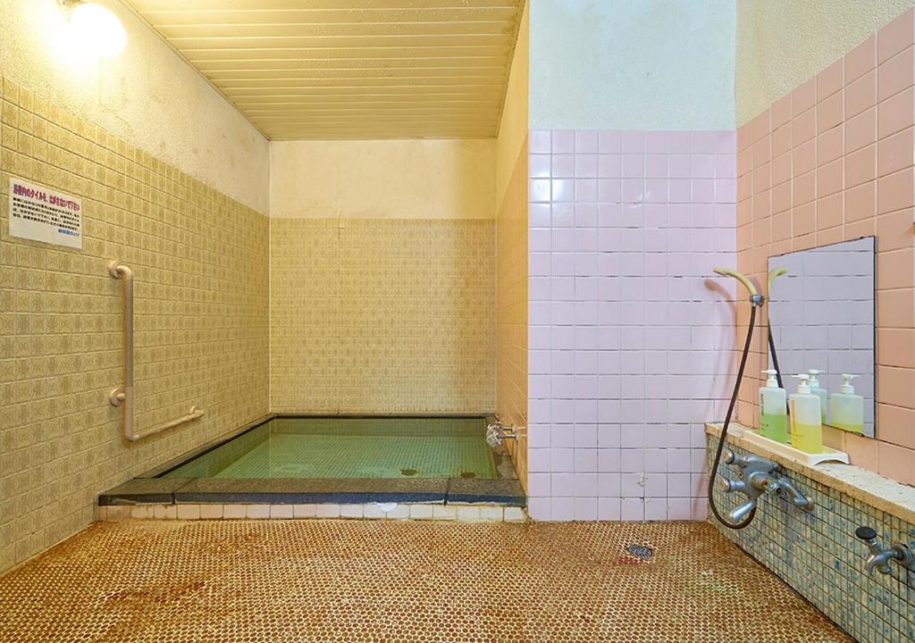 - une salle de bains avec baignoire dans une chambre revêtue de carrelage rose dans l'établissement Shinwaka Lodge, à Wakayama