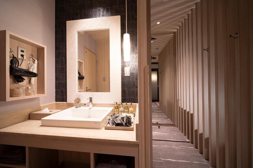 La salle de bains est pourvue d'un lavabo, d'un miroir et d'un couloir. dans l'établissement ホテル ポルト 男塾ホテルグループ, à Himeji