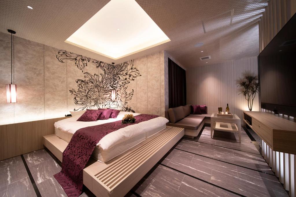 une chambre avec un grand lit et un canapé dans l'établissement ホテル ポルト 男塾ホテルグループ, à Himeji