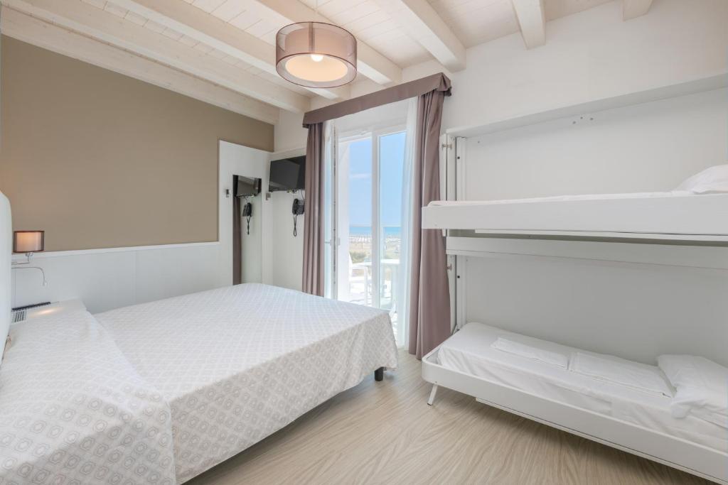 une chambre blanche avec deux lits et une fenêtre dans l'établissement Hotel Austria, à Caorle