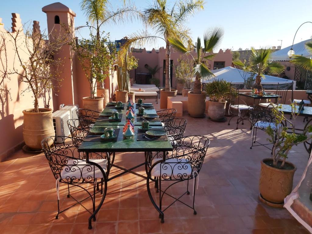 une table et des chaises sur une terrasse avec des plantes dans l'établissement Riad Les Nuits de Marrakech, à Marrakech