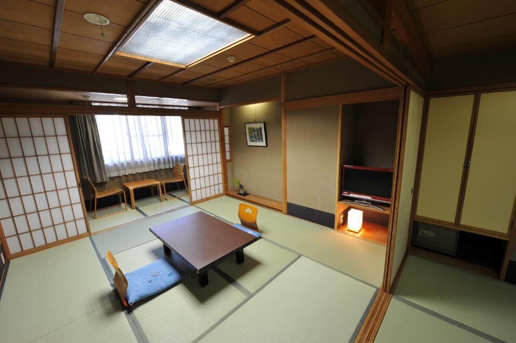 un salon avec une table et une télévision dans l'établissement Watazen Ryokan - Established in 1830, à Kyoto