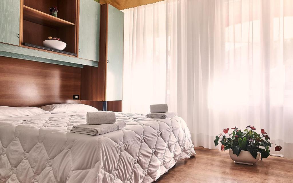 une chambre avec un lit avec des draps blancs et une fenêtre dans l'établissement Hotel Villa Roma, à Caorle 7 autres photos