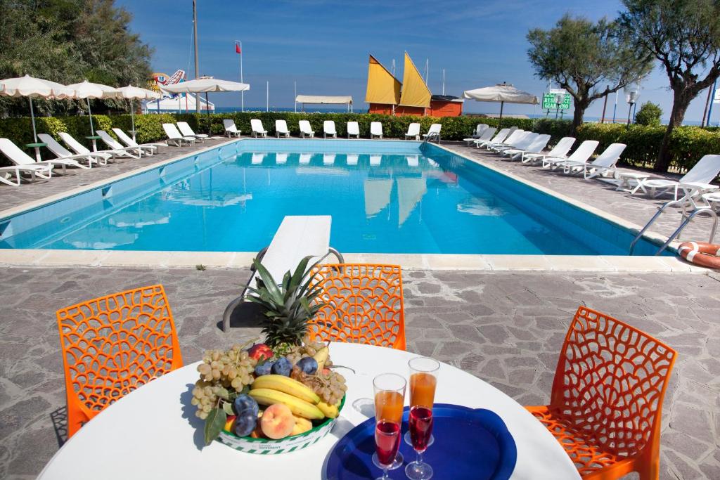 - une table avec un bol de fruits à côté de la piscine dans l'établissement Hotel Residenza Giardino, à Bellaria-Igea Marina