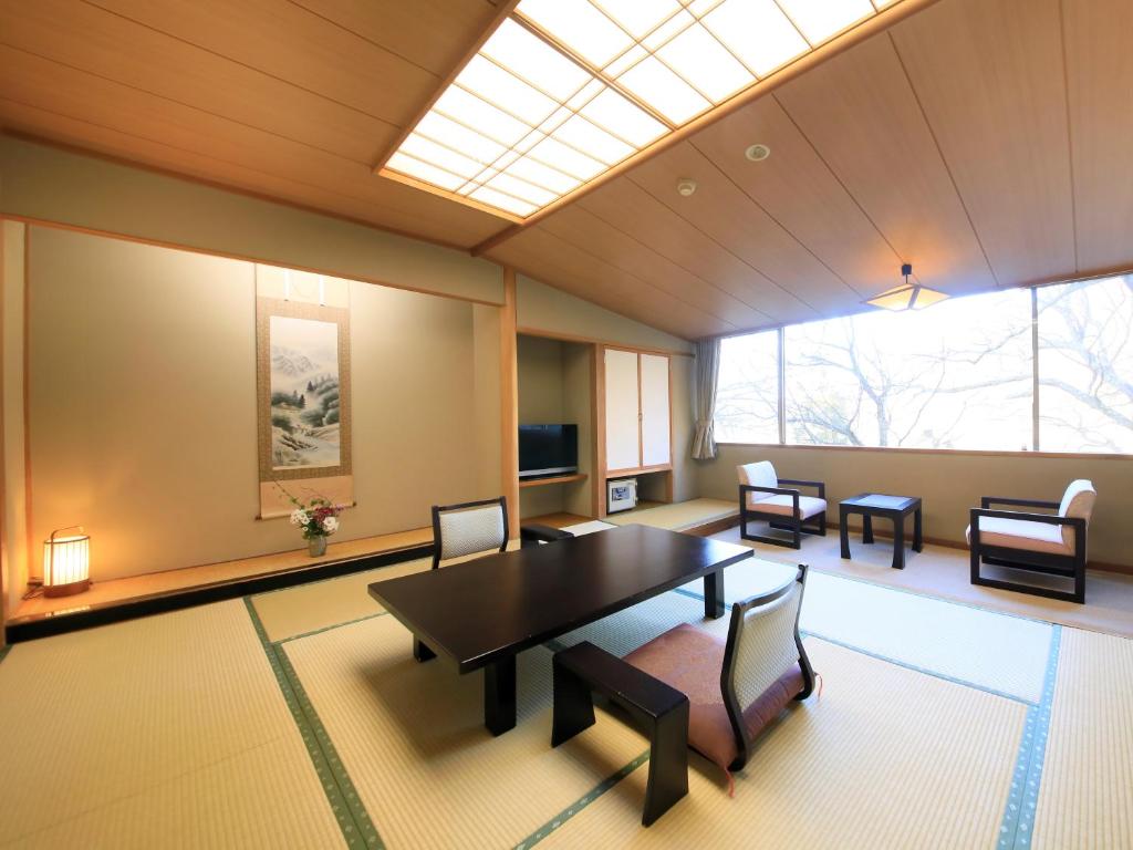 Cette grande chambre dispose d'une table, de chaises et d'une lucarne. dans l'établissement Ginshotei Awashima, à Numata