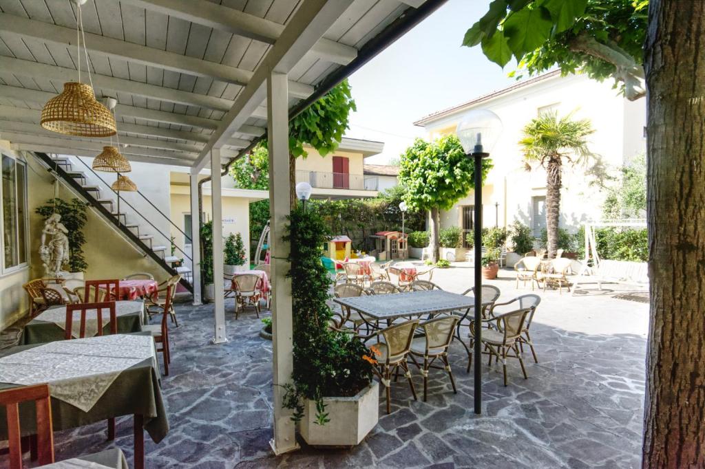 un patio extérieur avec tables, chaises et arbres dans l'établissement Hotel Pironi, à San Mauro a Mare