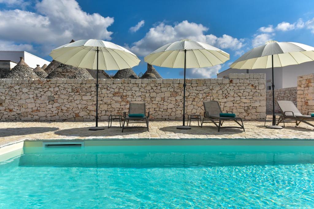 - une piscine avec 2 chaises longues et 2 parasols dans l'établissement Borgo Aratico, à Monopoli