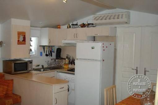 une cuisine avec un réfrigérateur blanc et un comptoir dans l'établissement Mobilhome sur camping le kontiki **** ramatuelle, à Saint-Tropez