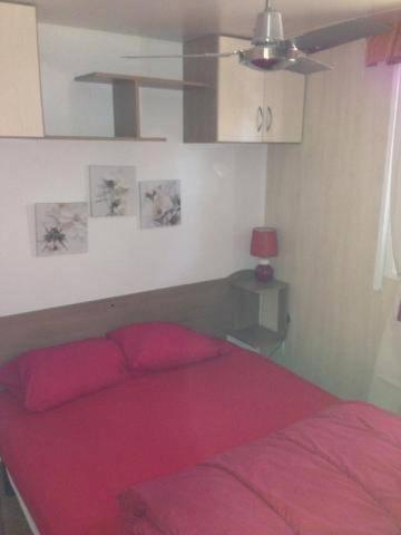 - une chambre avec un lit rouge et un ventilateur de plafond dans l'établissement Mobilhome sur camping le kontiki **** ramatuelle, à Saint-Tropez