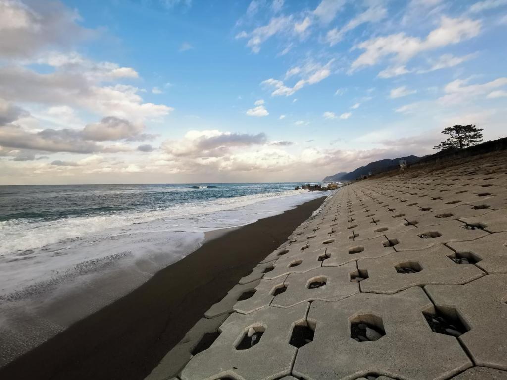 - une plage avec des rochers dans le sable dans l'établissement たから温泉民宿 Gem Onsen Stay, à Sakaimura