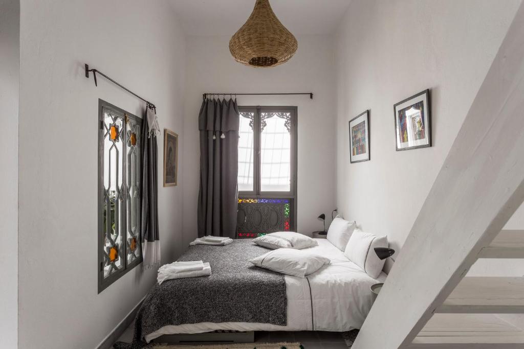 une chambre avec un lit avec des draps blancs et des oreillers dans l'établissement Riad Dar-tus, à Tanger