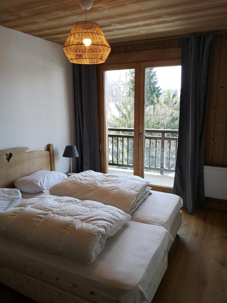 une chambre avec deux lits et une grande fenêtre dans l'établissement Chalet Les Combes, à Notre-Dame-de-Bellecombe