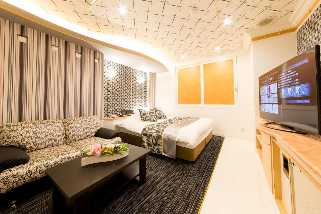 une chambre d'hôtel avec un lit, un canapé et une télévision dans l'établissement Hotel Brooks (Adult Only ), à Kasukabe