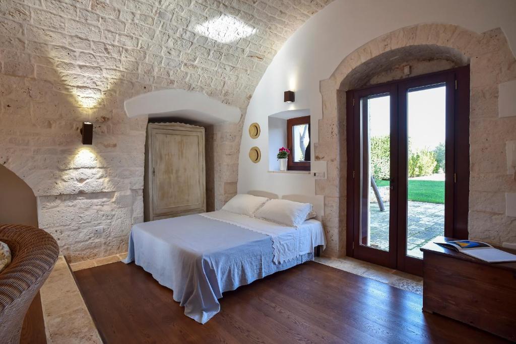 une chambre avec un lit et un mur en pierre dans l'établissement Casale Lillina, à Castellana Grotte