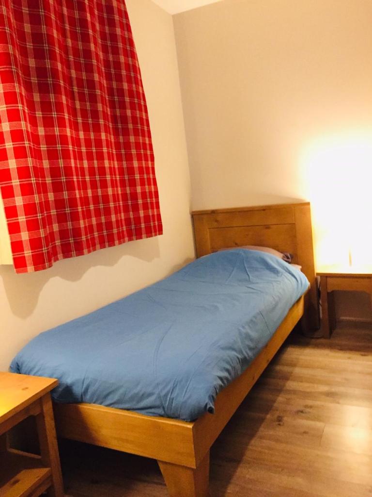 - un lit dans une chambre dotée d'un rideau tressé rouge dans l'établissement Duplex Familial à Vars, Chalets des Rennes, à Vars