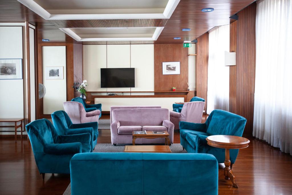 une salle d'attente avec des chaises bleues et une télévision à écran plat dans l'établissement Diana Grand Hotel, à Alassio