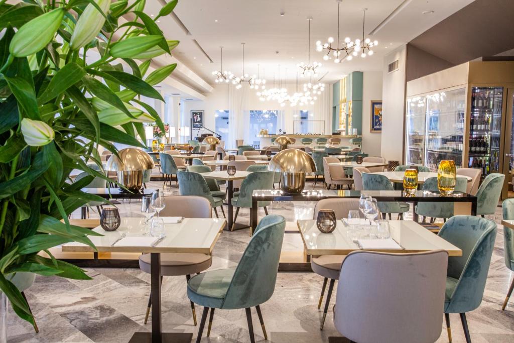 un restaurant avec des tables, des chaises et des plantes dans l'établissement Diana Grand Hotel, à Alassio