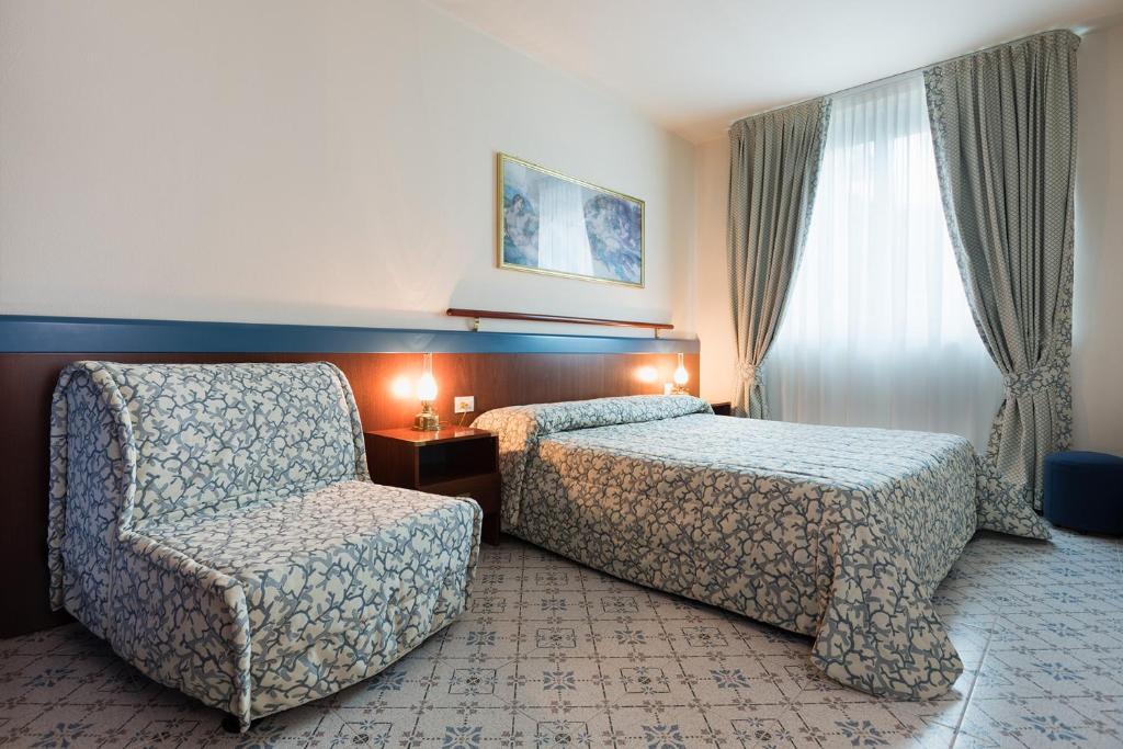une chambre d'hôtel avec un lit et une chaise dans l'établissement Aparthotel Holiday, à Bibione