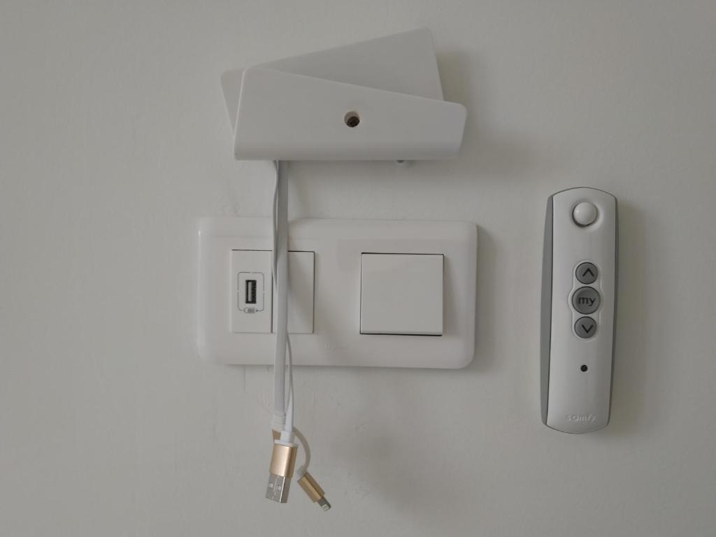 un mur blanc avec une prise électrique et un régulateur dans l'établissement Les Gîtes du Château de Passillé, à Parigné