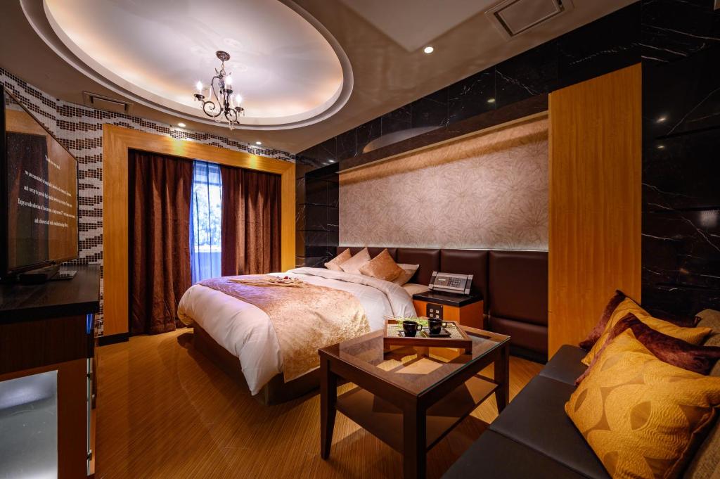 une chambre avec un lit, une table et un canapé dans l'établissement HOTEL ZEN KOHOKU, à Yokohama