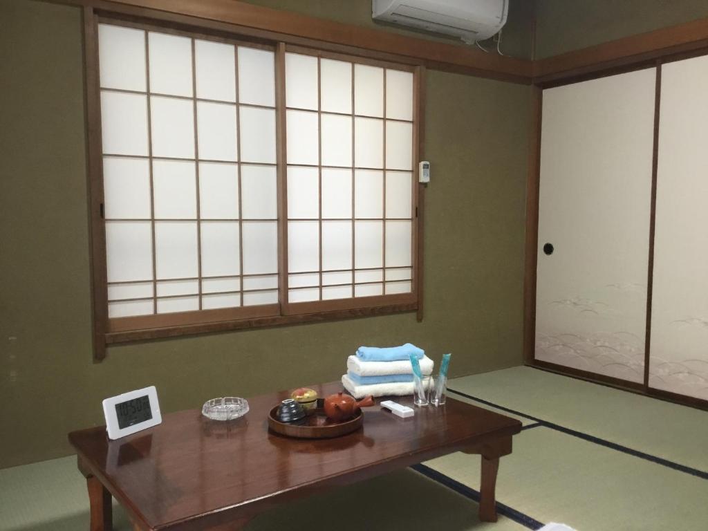 Cette chambre dispose d'une table en bois et de deux fenêtres. dans l'établissement Hamayuu, à Higashiizu