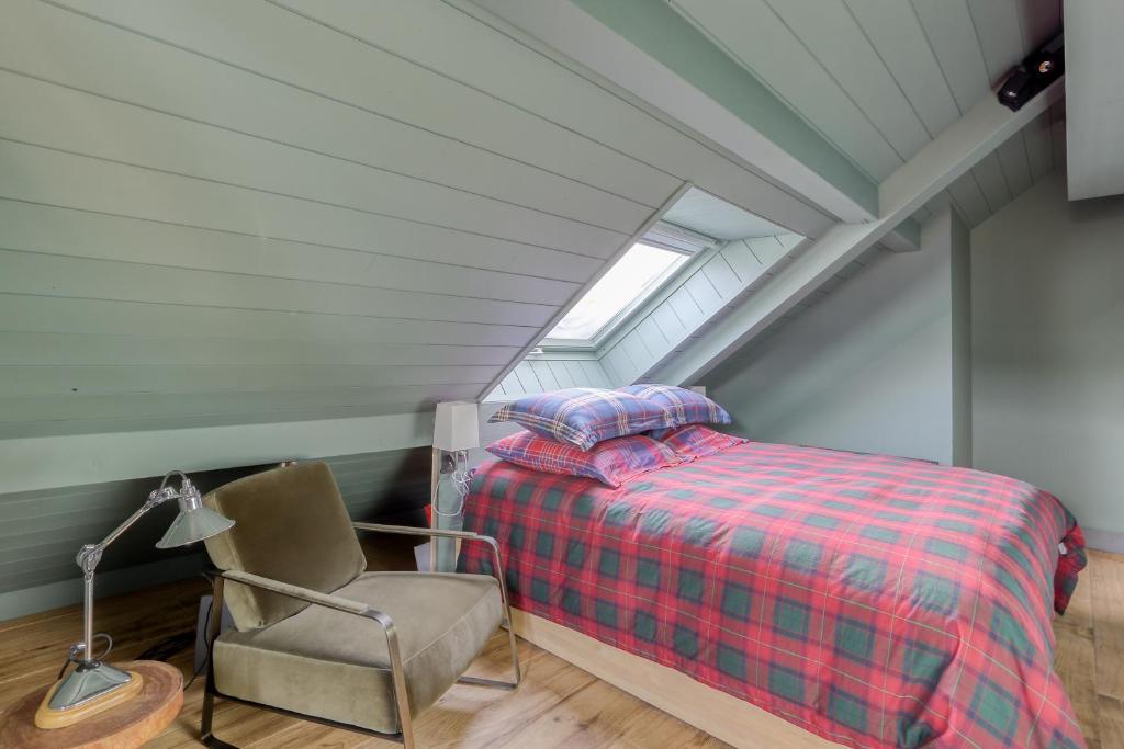 une chambre mansardée avec un lit et une chaise dans l'établissement Prestigieux Appartement Pied Piste Luc Alphand 80 M2 Serre Chevalier Chantemerle, à Saint-Chaffrey