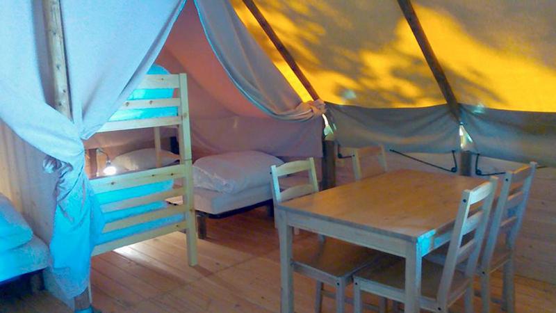 une tente avec une table, un lit, une table et des chaises dans l'établissement Camping le Nid du Parc, à Villars-les-Dombes