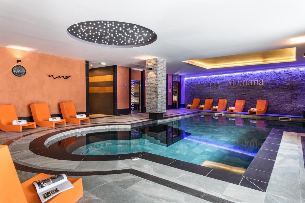 - une piscine dans le hall de l'hôtel avec des chaises orange dans l'établissement Residence Montana Plein Sud, à Val Thorens