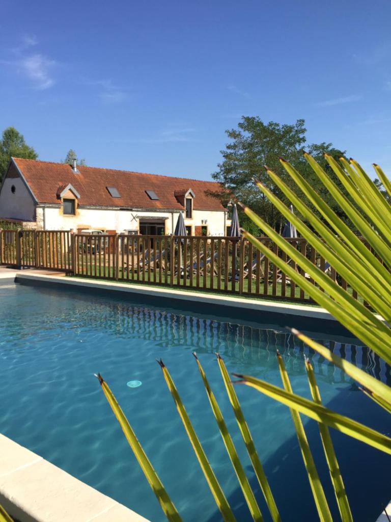 - une piscine en face d'une maison avec une clôture en bois dans l'établissement Village Toue du Domaine des Demoiselles, à Chassenard