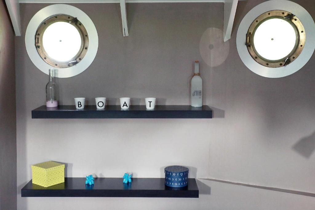 - une salle de bains avec deux miroirs et une étagère avec une bouteille dans l'établissement Le grand large, à Metz