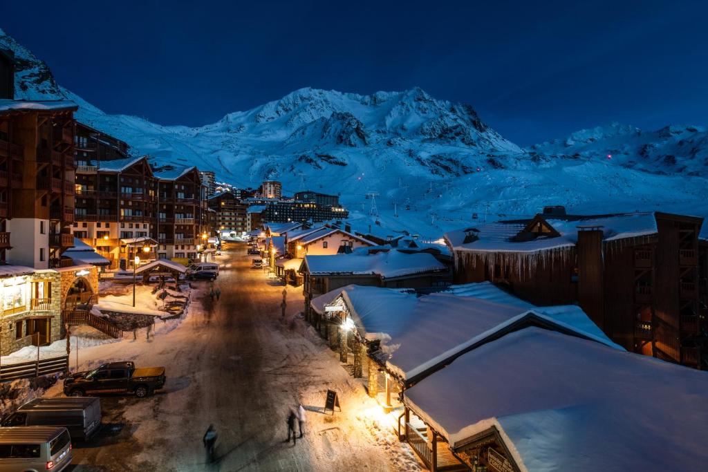 une ville dans la neige la nuit avec une montagne dans l'établissement Le Cheval Blanc - Village Montana, à Val Thorens