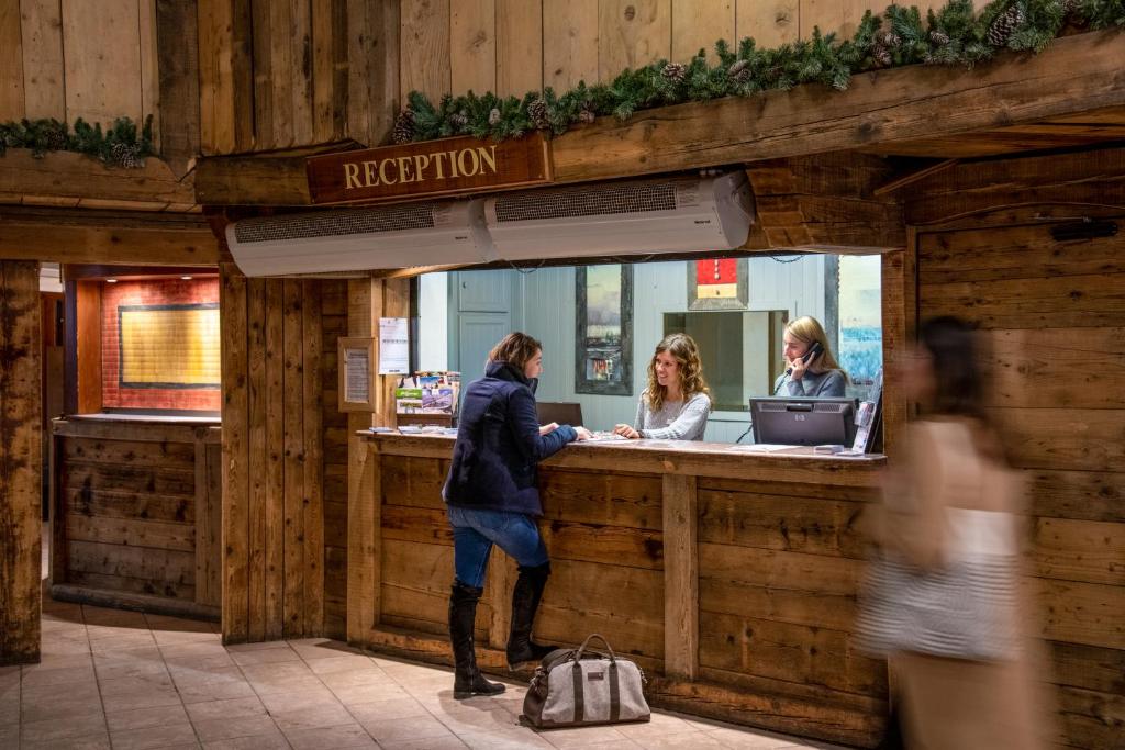 un homme debout à la réception d'un restaurant dans l'établissement Le Cheval Blanc - Village Montana, à Val Thorens