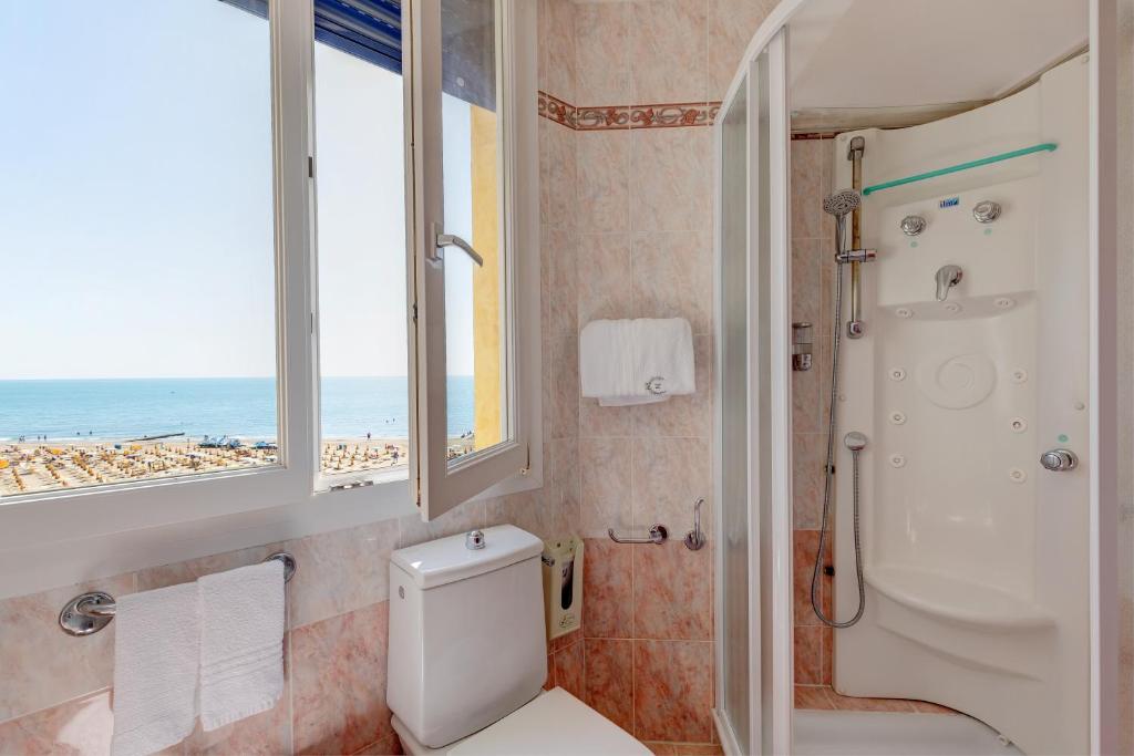 une salle de bain avec douche et toilettes et une fenêtre dans l'établissement Hotel Napoleon, à Lido di Jesolo