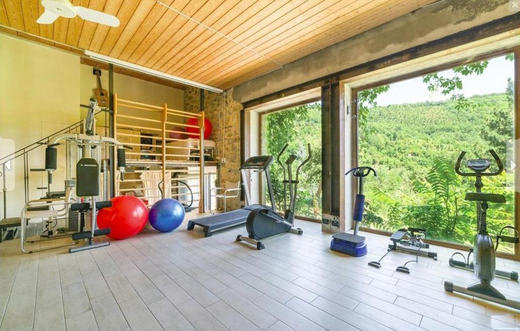 une salle de sport avec des équipements de remise en forme et une grande fenêtre dans l'établissement DeiMori LaMassa private villa with pool, à Castel San Niccolò