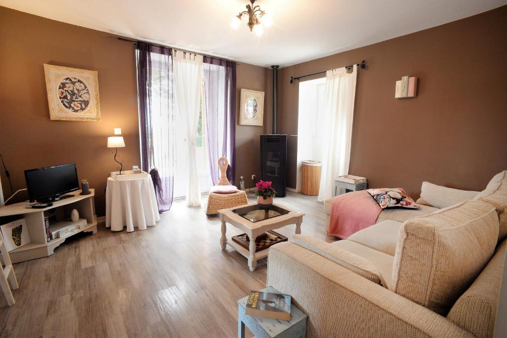 un salon avec un canapé et une télévision dans l'établissement Les Gîtes de La Treille, à Montagrier