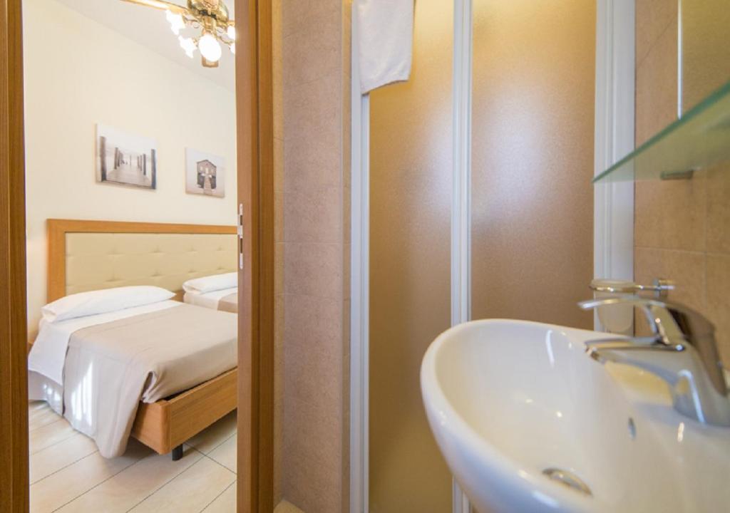une salle de bain avec un lavabo et un lit dans l'établissement Mediterraneo Hotel & Suites, à Cattolica