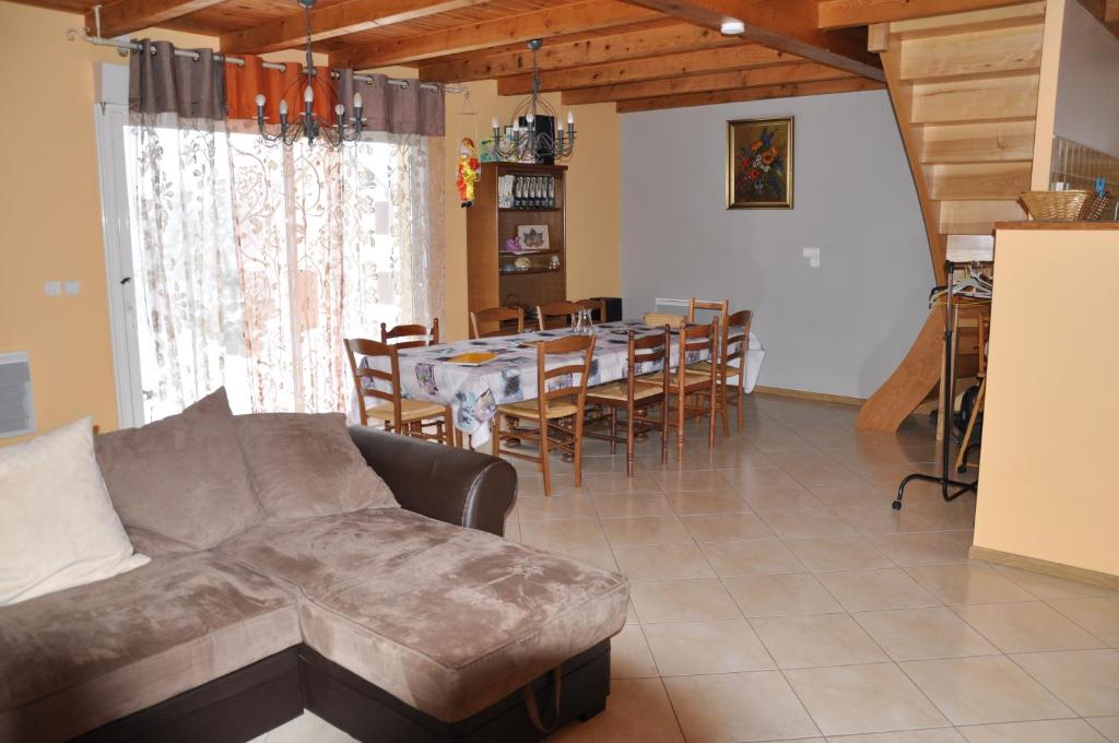 un salon avec un canapé et une table avec des chaises dans l'établissement Brameloup, à Prades-dʼAubrac