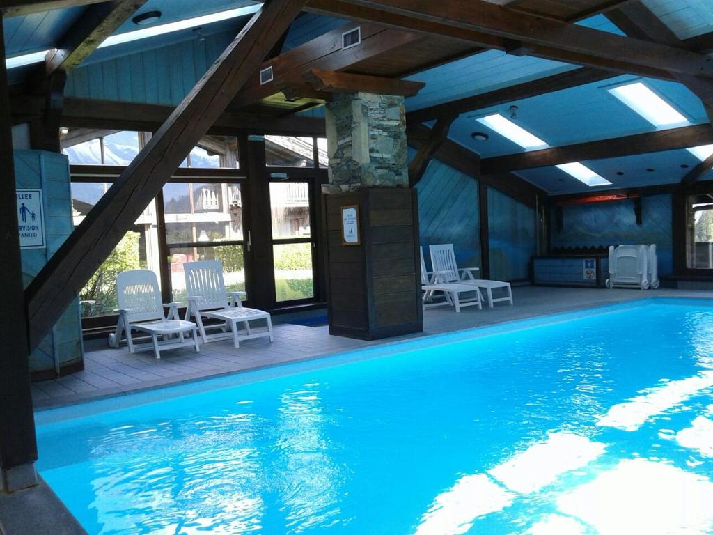 une grande piscine avec des chaises dans un bâtiment dans l'établissement La clé des montagnes, aux Houches
