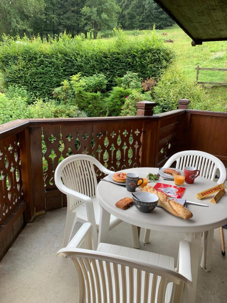 - une table et des chaises blanches avec de la nourriture sur une terrasse couverte dans l'établissement La clé des montagnes, aux Houches
