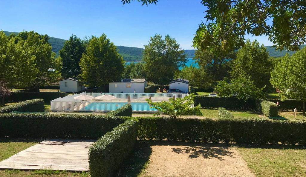 un jardin avec une piscine et quelques buissons dans l'établissement LES BASTIDES DE CHANTERAINE Bungalows, Lodges & Spa, à Aiguines