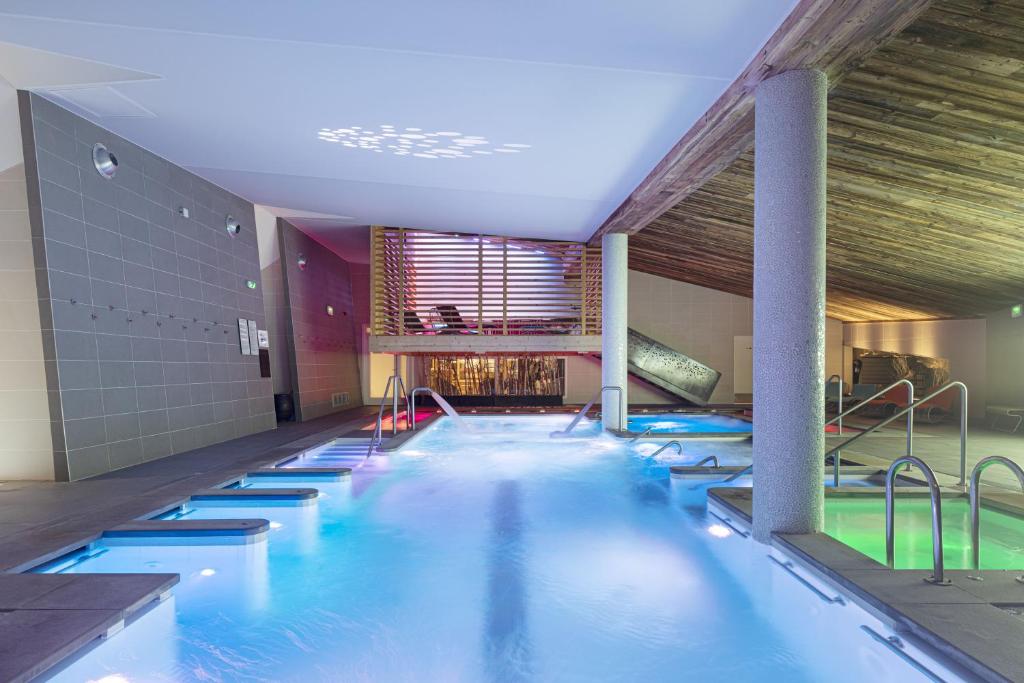 une grande piscine avec de l'eau bleue dans un immeuble dans l'établissement Hotel Le Chabichou, à Courchevel