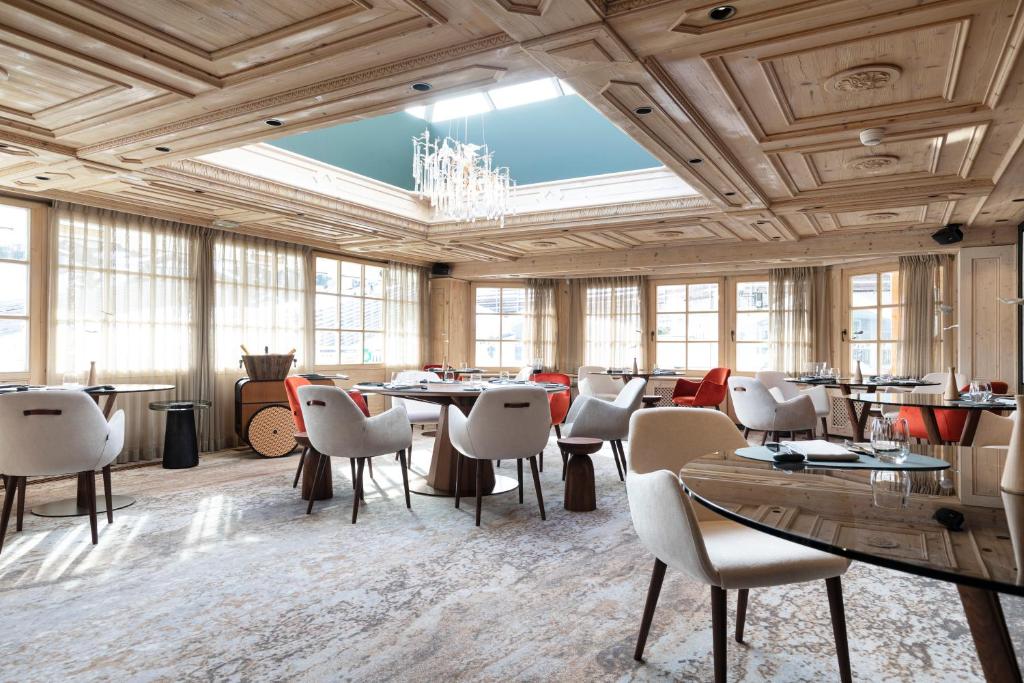 une grande pièce avec des tables, des chaises et un lustre dans l'établissement Hotel Le Chabichou, à Courchevel