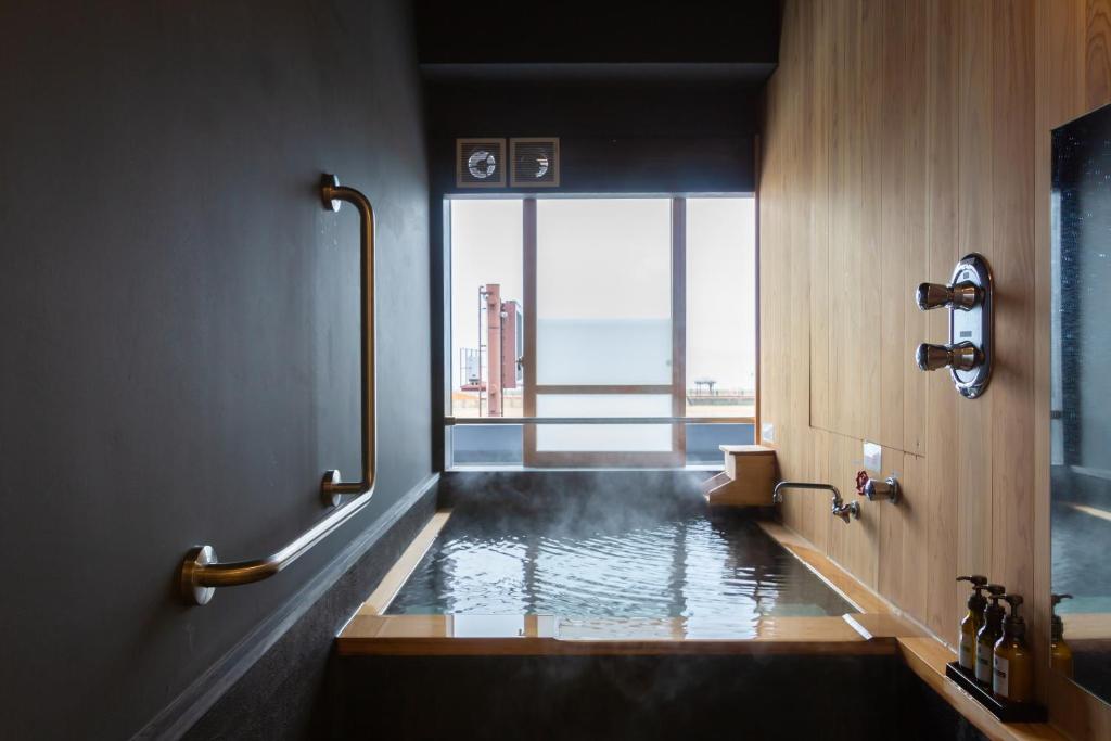 La salle de bains est pourvue d'une baignoire et d'une fenêtre. dans l'établissement Iseya, Seaview Private Oceanside Bath, à Unzen