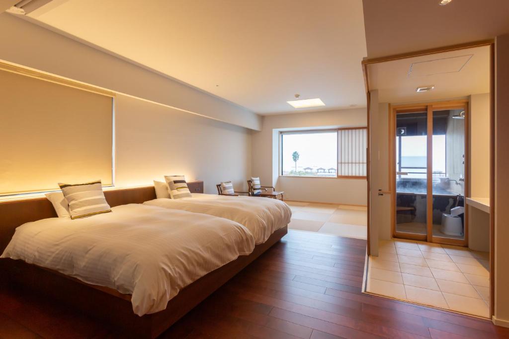 un grand lit dans une chambre avec une grande fenêtre dans l'établissement Iseya, Seaview Private Oceanside Bath, à Unzen