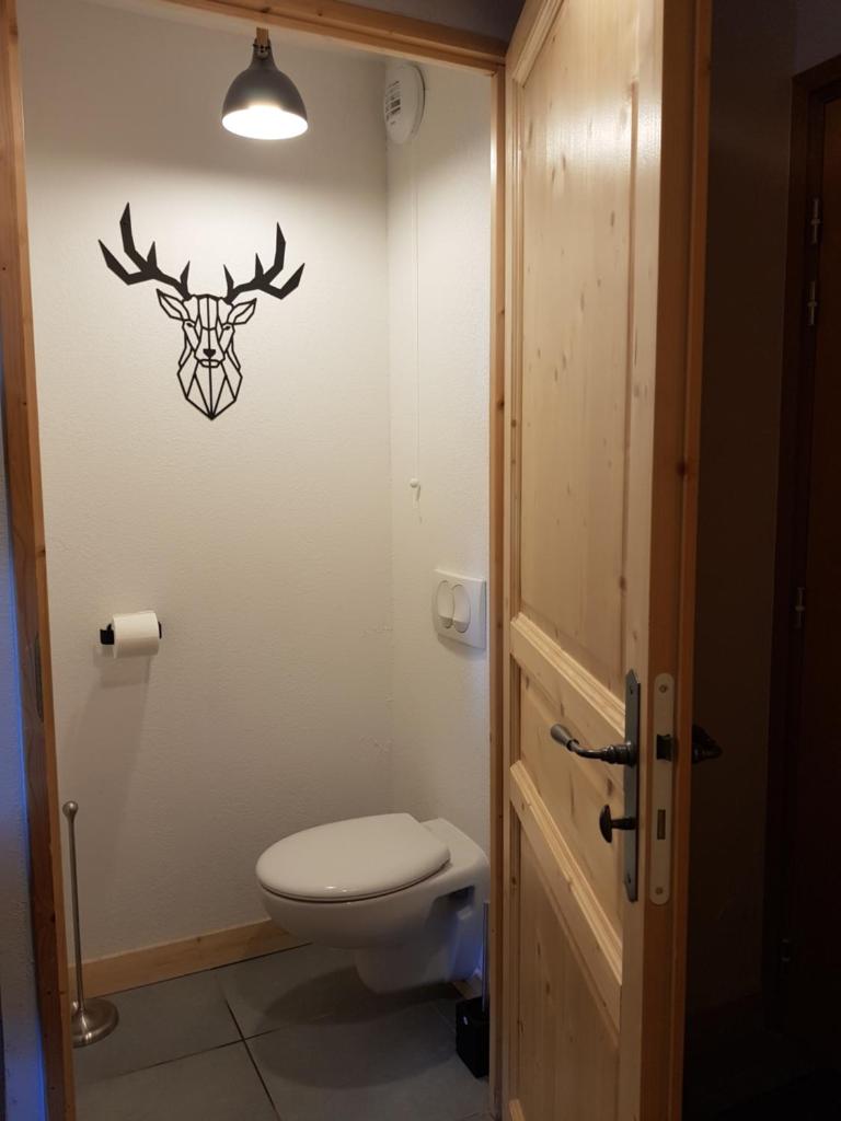 La salle de bains est pourvue de toilettes et d'une vignette de cerf sur le mur. dans l'établissement Résidence : Le Crystal Chalet, à Les Deux Alpes 33 autres photos