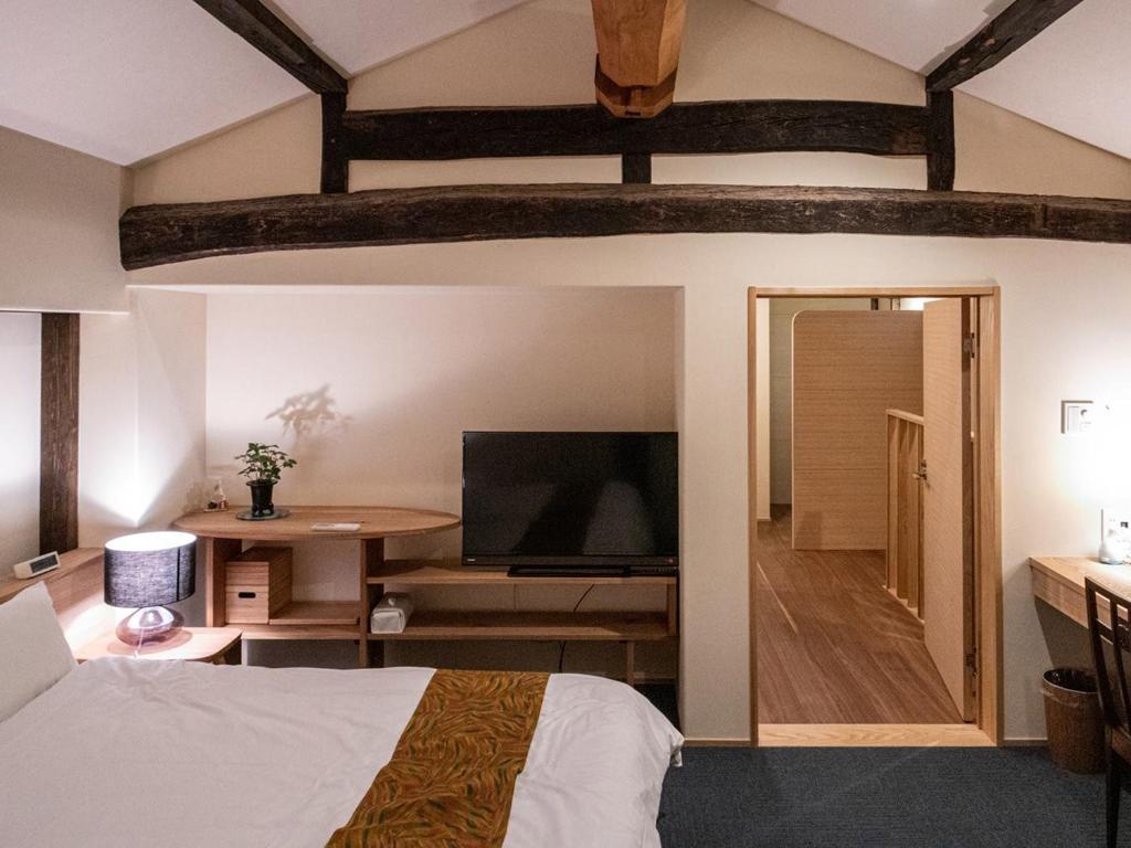 une chambre avec un lit et une télévision à écran plat dans l'établissement 内子の宿 久, à Uchiko