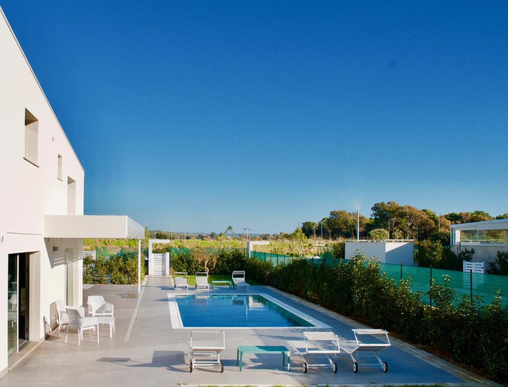 - une piscine à côté d'un bâtiment avec des chaises dans l'établissement villa MAMA Marina di ragusa, à Marina di Ragusa